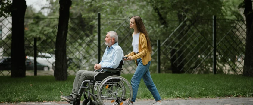 Praca opiekunki w Niemczech bywa przyjemna, gdy. Opiekunka spaceruje z seniorem po parku.